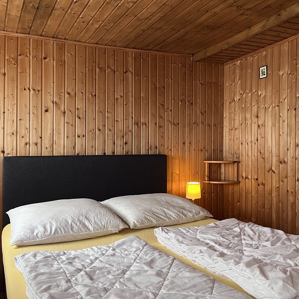 Doppelbett mit Kopfkissen und Bettdecke im Schlafzimmer eines Bungalows